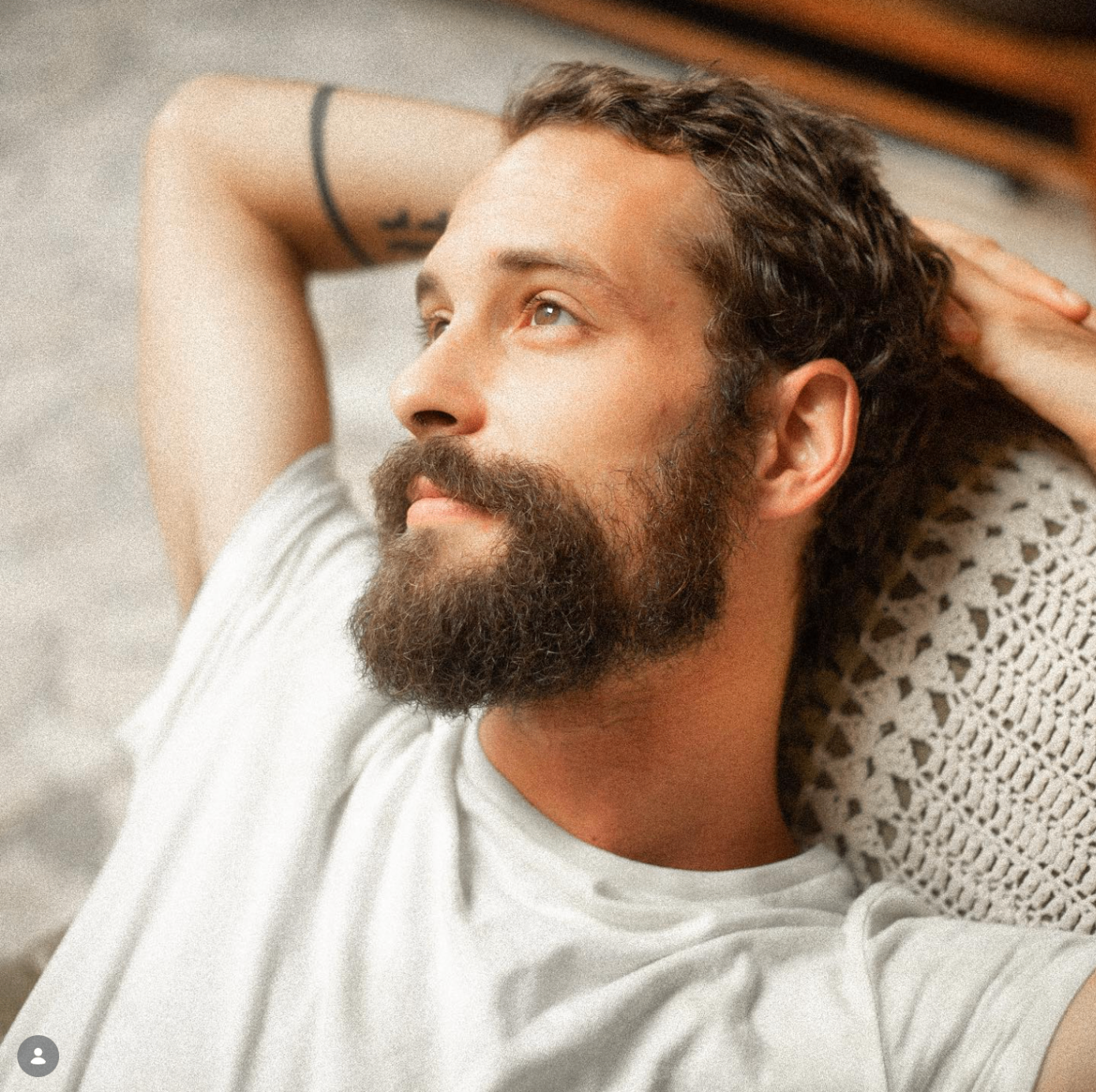 Teo Luz lying back with hands behind his head, looking up, bearded, in a white t-shirt